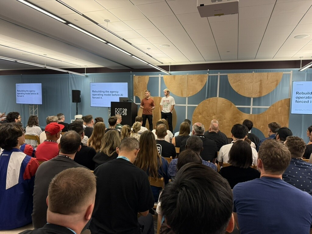 Two presenters speaking to a seated audience at a conference.